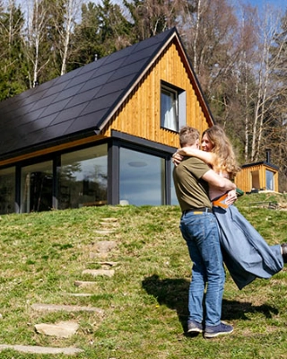 Paar umarmt sich vor ihrem energieeffizienten Zuhause. 